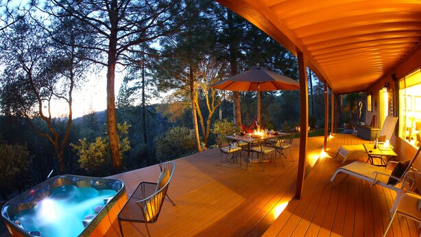 Eine Holzterrasse mit Whirlpool, Sitzgelegenheiten im Freien und einem Feuerkorb.