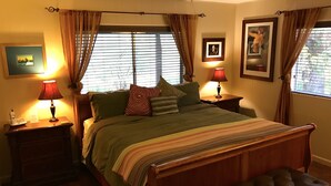 Ein Schlafzimmer mit einem großen Bett, zwei Nachttischen mit Lampen, einer Bank am Fußende des Bettes und einem Fenster mit Vorhängen.