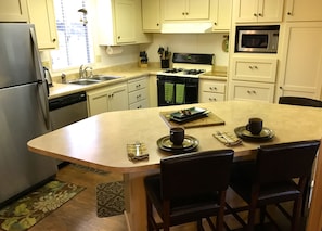 Enjoy cooking in this well-equipped kitchen with a central island, sink, stove, microwave, and dishwasher.