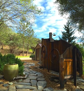 Surrounded by nature, this charming cabin features a stone pathway and a large potted plant.