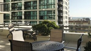 Una terraza en la azotea con asientos al aire libre, una planta en maceta y vistas a un edificio de gran altura.