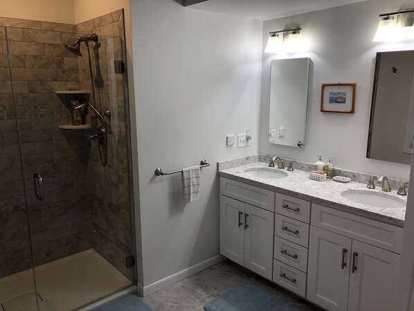 Une salle de bain moderne avec une douche à parois de verre, un meuble-lavabo blanc et un grand miroir.