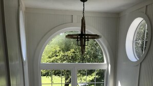 Eine Treppe mit Blick auf einen üppigen Garten durch ein großes Rundbogenfenster.