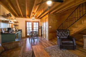 Un intérieur en bois comprenant un coin repas, un fauteuil en cuir et un escalier.