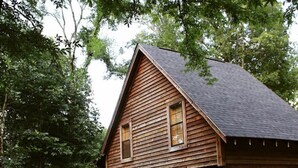 A wooden cabin with a porch, a staircase, and a small deck.