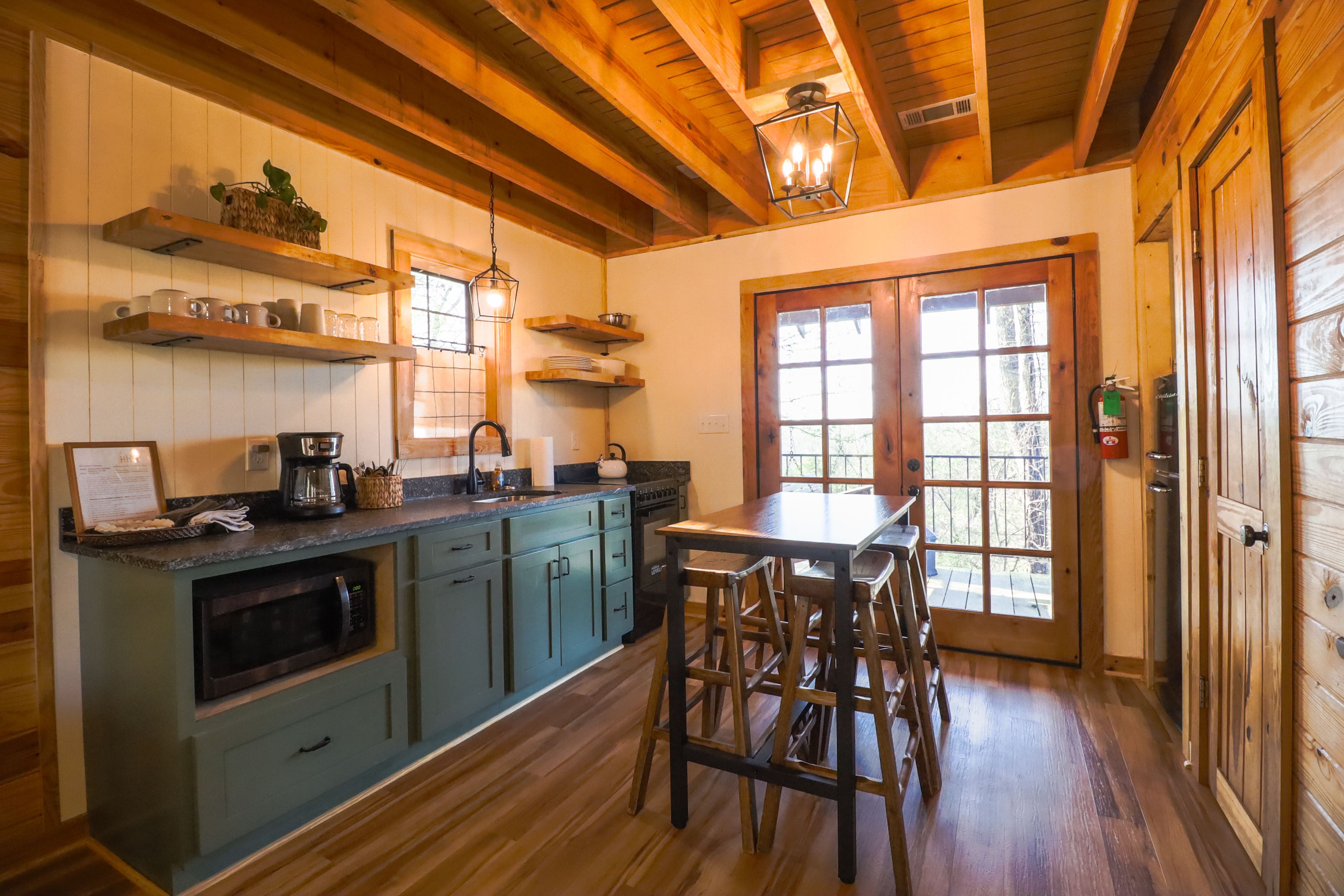 A kitchen with wooden cabinets, a coffee maker, and a dining area with stools.