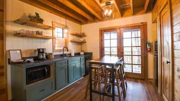 A kitchen with wooden cabinets, a coffee maker, and a dining area with stools.