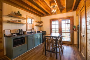 A kitchen with wooden cabinets, a coffee maker, and a dining area with stools.