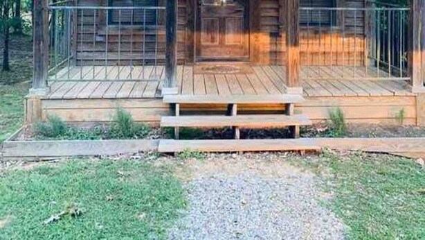 A wooden cabin with a porch, a front door, and windows.