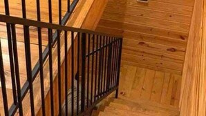 A wooden staircase with a metal railing, leading to a lower level.