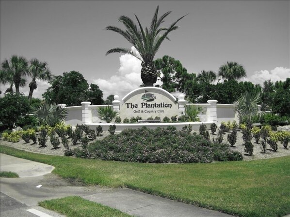Welcome to The Plantation Golf & Country Club, where lush gardens and a scenic pathway lead to the entrance.