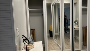 Un couloir avec un miroir, un bureau et des portes coulissantes en verre donnant sur une pièce.