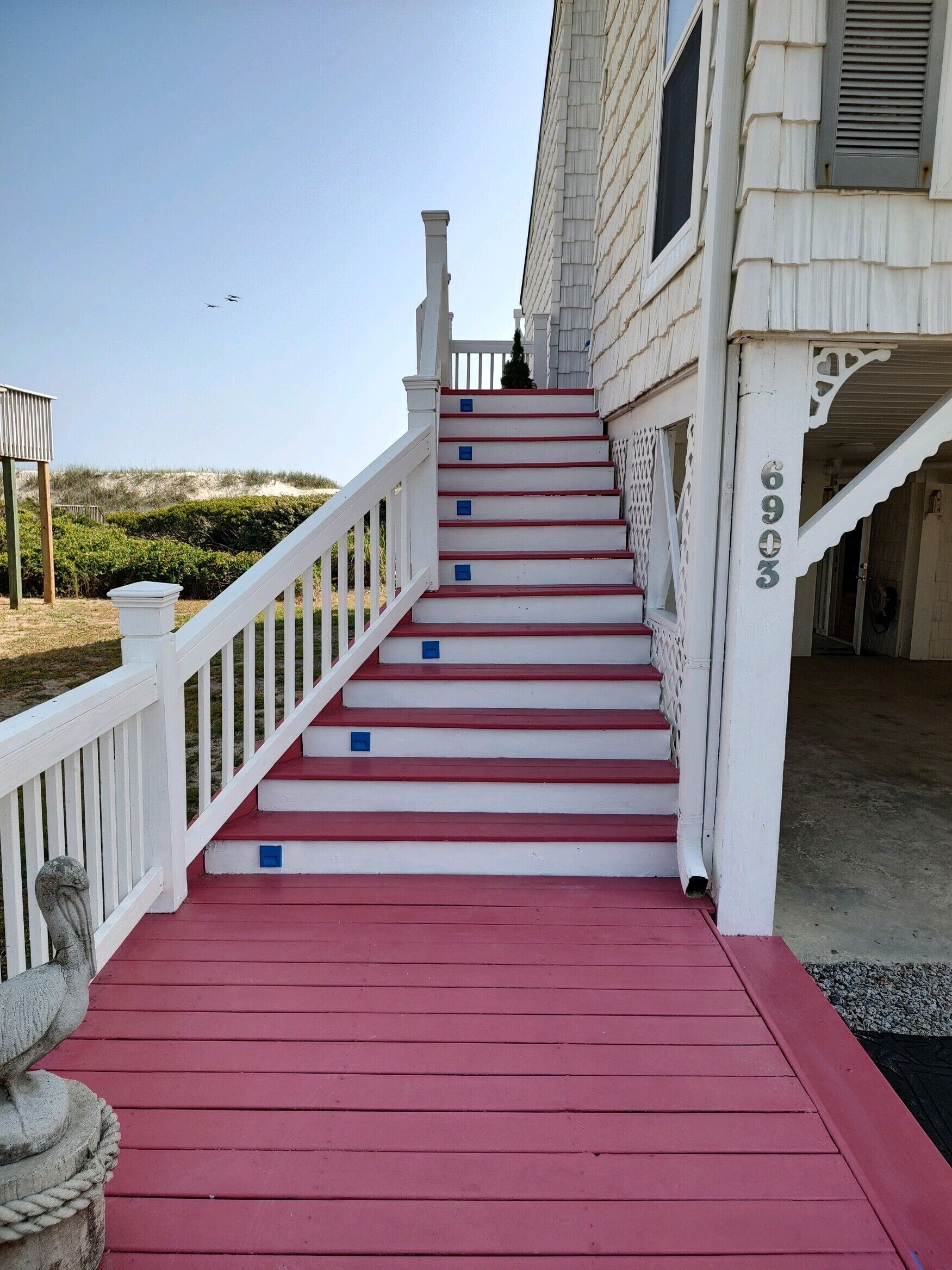 A staircase with red steps leading up to a white building with a number 6903 on the side.