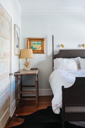Une chambre à coucher avec un lit en bois, une table de chevet avec une lampe et un tableau encadré au mur.