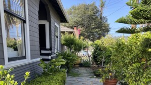 A stone pathway leading to a house with a porch, surrounded by various plants and a small garden area. - Central A/C, heat, Fireplace, Off-Street Parking, fenced yard (Santa Barbara)