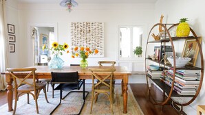 A dining area with a wooden table, four chairs, a vase with flowers, a bookshelf, and a decorative pineapple. - Central A/C, heat, Fireplace, Off-Street Parking, fenced yard (Santa Barbara)