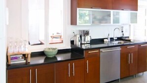 A modern kitchen with wooden cabinets, a stainless steel dishwasher, and pendant lighting. - Central A/C, heat, Fireplace, Off-Street Parking, fenced yard (Santa Barbara)