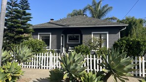 A two-story house with a gray exterior, white trim, and a small front porch. - Central A/C, heat, Fireplace, Off-Street Parking, fenced yard (Santa Barbara)