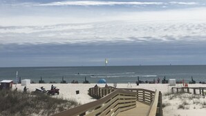 A beach with a wooden boardwalk leading to the water, a lifeguard tower, and beach chairs and umbrellas. - 🏖 Beach front 3 bedroom 2 bath and 3 balconies corner unit extra balconies (Gulf Shores)