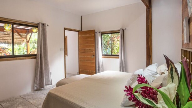 Une chambre à coucher avec un lit, deux fenêtres et un plafond en bois.