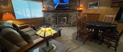 A cozy living room with a fireplace, a television, and a dining area.