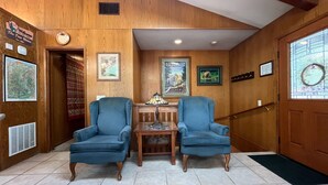 A wooden interior with two blue armchairs, a small table, and a poster on the wall. - (48R) The Tree House II at The Redwoods In Yosemite (Yosemite National Park)