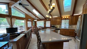 A spacious kitchen with a large island, wooden cabinets, and a dining area with a TV and comfortable seating. - (48R) The Tree House II at The Redwoods In Yosemite (Yosemite National Park)