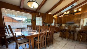 A kitchen with wooden cabinets, a dining table with chairs, and a hanging light fixture. - (48R) The Tree House II at The Redwoods In Yosemite (Yosemite National Park)