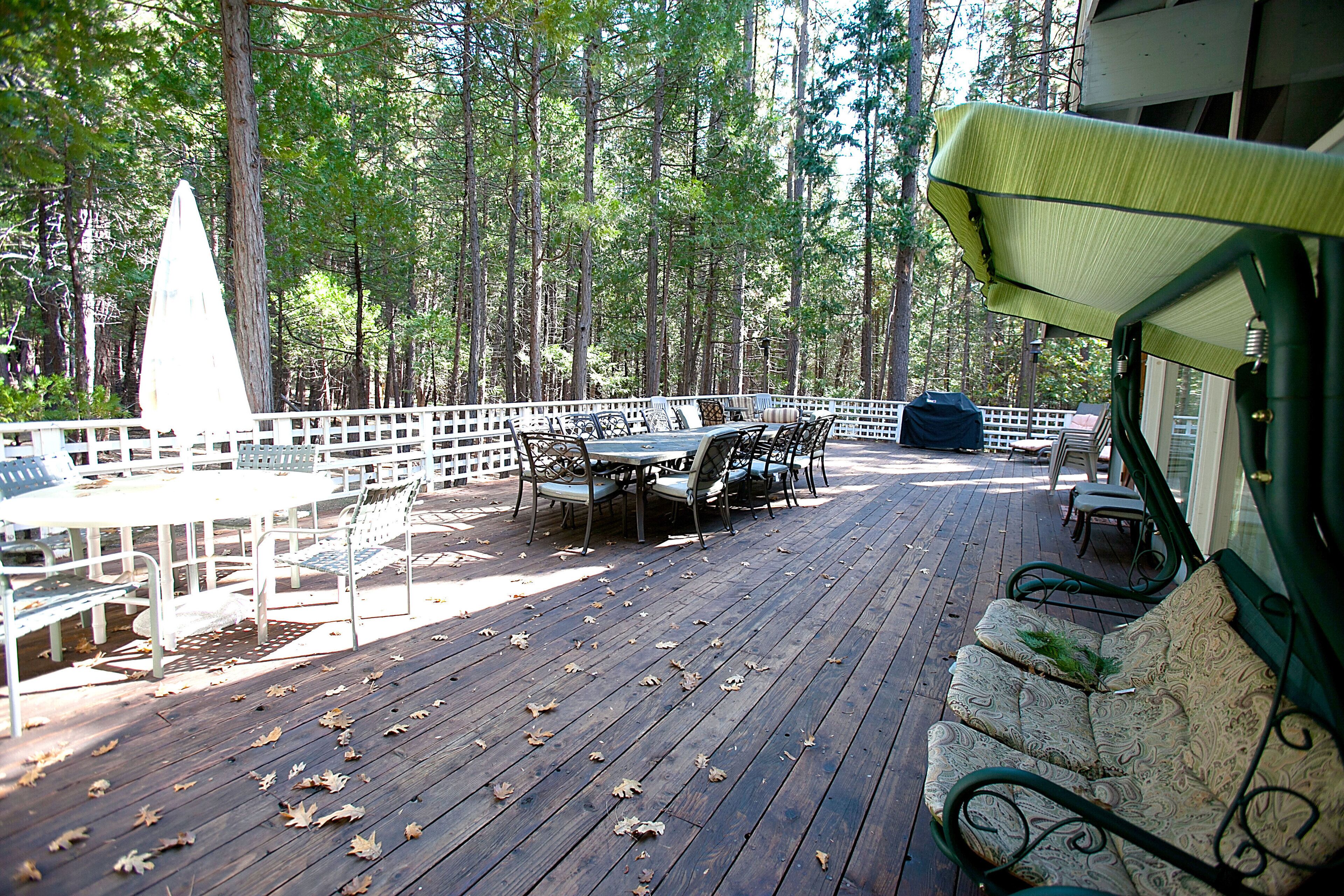 A wooden deck with outdoor furniture, surrounded by trees.