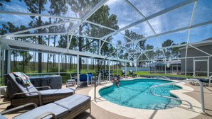 Un área de piscina al aire libre con sillas de descanso y un jacuzzi bajo una estructura cubierta.