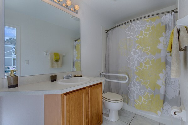 A bathroom with a white sink, a toilet, and a shower curtain with a floral pattern.