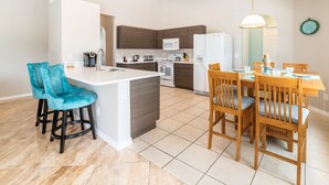 Una cocina moderna con una isla central, taburetes de bar y una mesa de comedor con sillas.