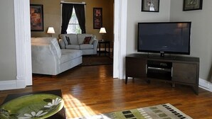 A living room with a sofa, TV, and a small table with lamps.