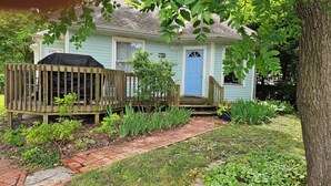 A house with a deck, a blue door, and a brick pathway leading to the front.