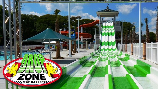Ein Wasserpark mit einer grün-weißen Rutsche, einer roten Rutsche und einem Pavillon.