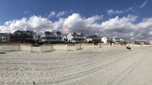 Ein Sandstrand mit Holzzaun und Häusern direkt am Strand.