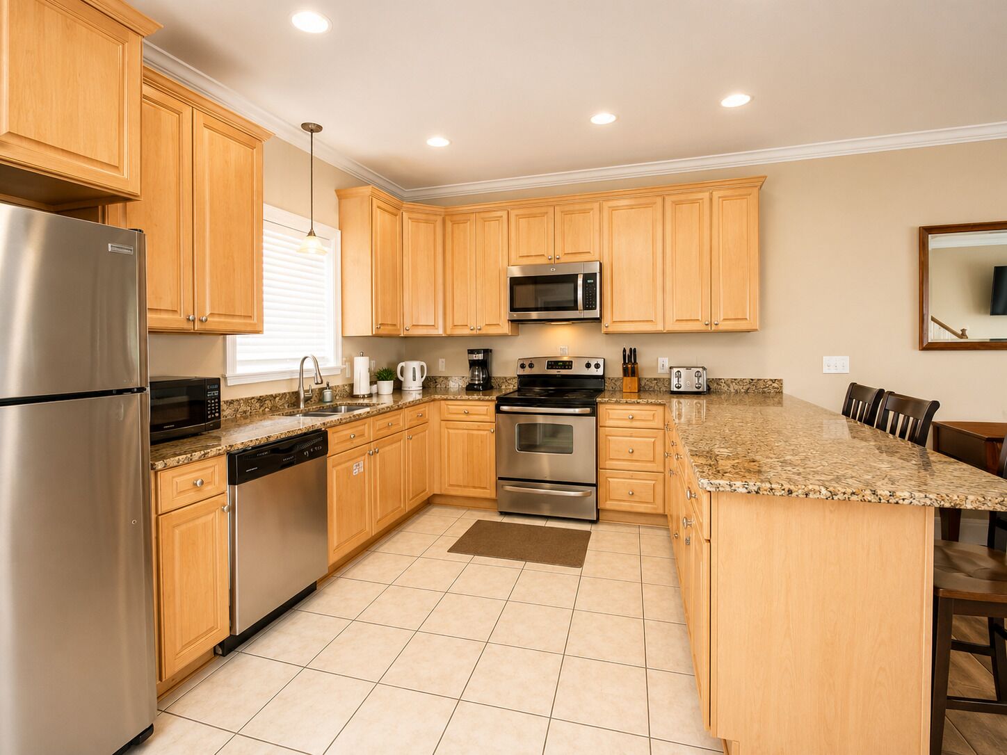 A modern kitchen with wooden cabinets, stainless steel appliances, and a granite countertop.