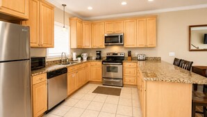 A modern kitchen with wooden cabinets, stainless steel appliances, and a granite countertop. - Last Minute Rates, Beach Front Home, 3Beds, 3.5 Bath, Full Ocean View (Panama City Beach)