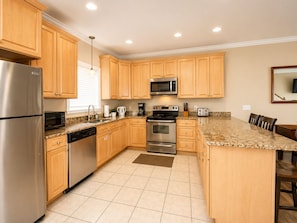 A modern kitchen with wooden cabinets, stainless steel appliances, and a granite countertop. - Last Minute Rates, Beach Front Home, 3Beds, 3.5 Bath, Full Ocean View (Panama City Beach)