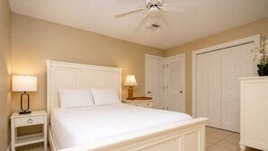 A hotel room with a bed, nightstands, a ceiling fan, and white doors. - Last Minute Rates, Beach Front Home, 3Beds, 3.5 Bath, Full Ocean View (Panama City Beach)