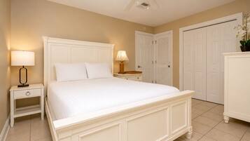 A hotel room with a bed, nightstands, a ceiling fan, and white doors.