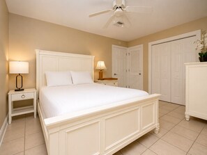 A hotel room with a bed, nightstands, a ceiling fan, and white doors. - Last Minute Rates, Beach Front Home, 3Beds, 3.5 Bath, Full Ocean View (Panama City Beach)