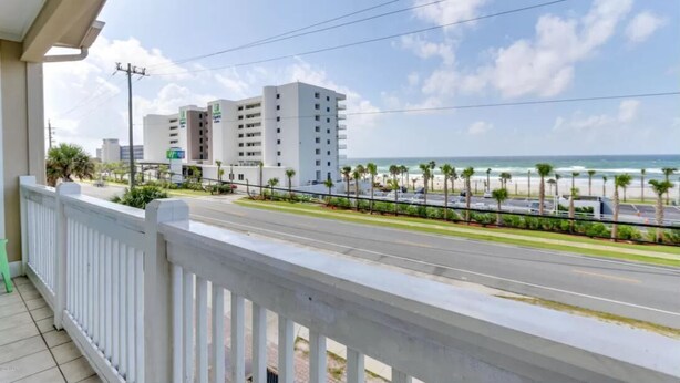 A balcony with a view of a beach, a road, and a parking lot. - Last Minute Rates, Beach Front Home, 3Beds, 3.5 Bath, Full Ocean View (Panama City Beach)