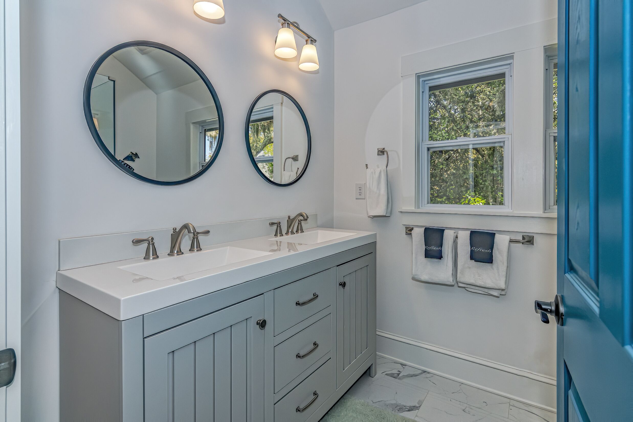 A bathroom with two sinks, a window, and a door.