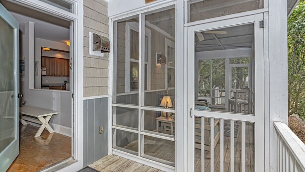 A covered porch with a sign reading "By the Sea." - Charming cottage in Sabal Palm with screened in porch and outdoor shower (Bald Head Island)