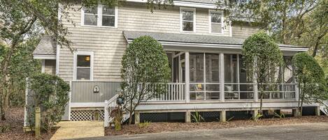A two-story house with a covered porch, a small front yard, and a wooden staircase leading to the entrance.