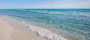 A beach with clear turquoise water and a sandy shore.