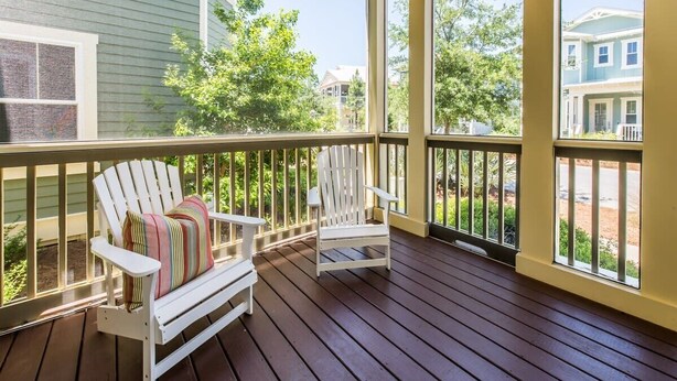 A wooden deck with two white Adirondack chairs, one with a striped cushion.