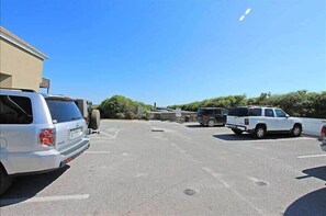 A parking lot with several vehicles, including a white SUV and a white pickup truck.