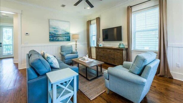 A living room with a sofa set, a coffee table, a TV, and a window with curtains.